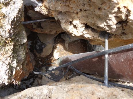 The space between the slabs forming the base of the tufa tower showing the two steel bars, the irrigation tube going into the base of the four-inch (10 cm) pipe, the two irrigation tubes beside the pipe, and the mortar between south and west slabs at the upper left.