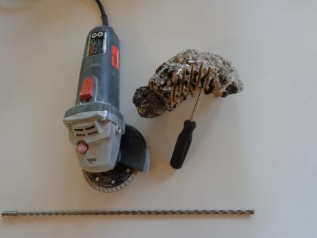 Tools and techniques for shaping tufa:  A 4.5 inch (11 cm) angle grinder (top left), tufa with parallel cuts ready to be snapped off with a screwdriver (top right), and a masonry drill bit (bottom). 